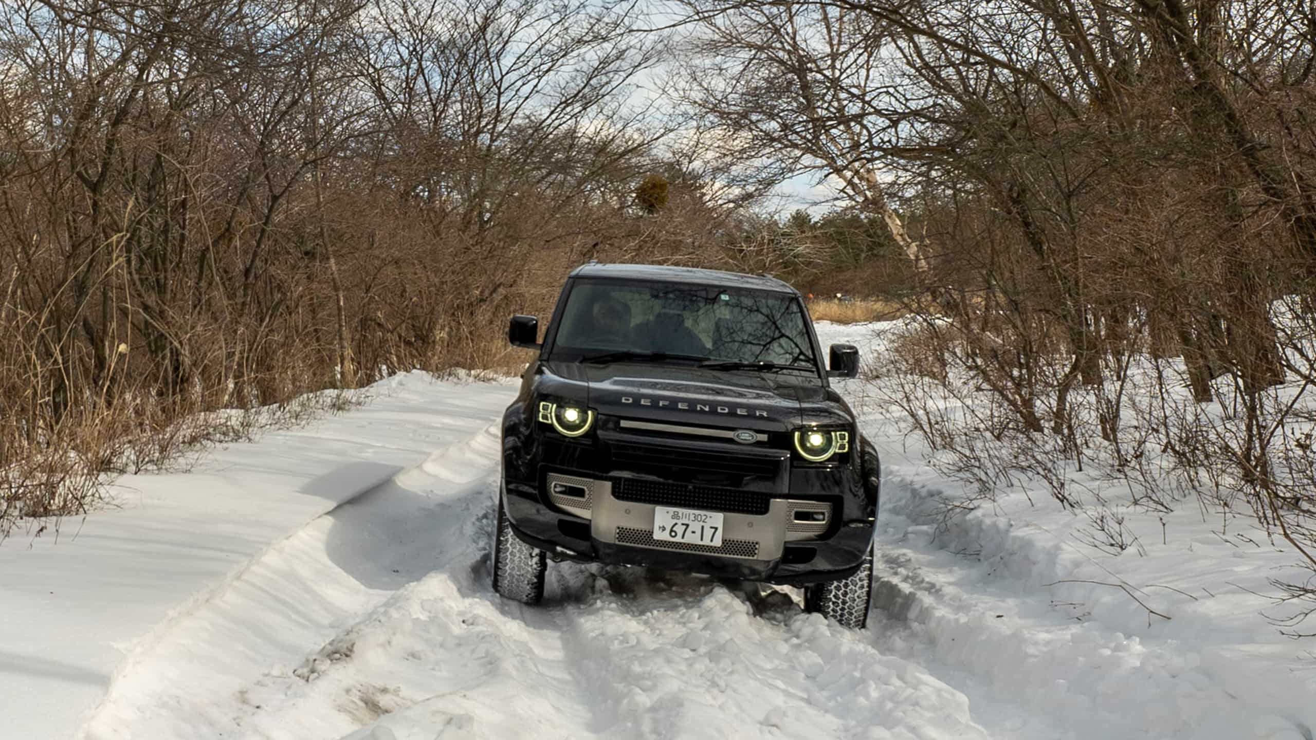 Land Rover Defender moving on a Snow Forest Road