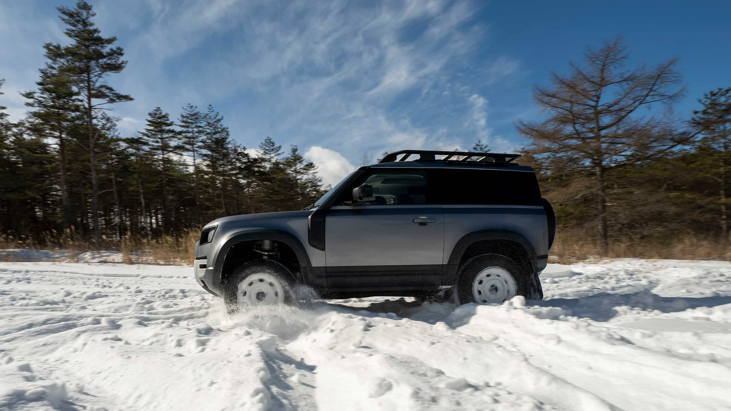 Land Rover Defender moving on a Snow Forest Road